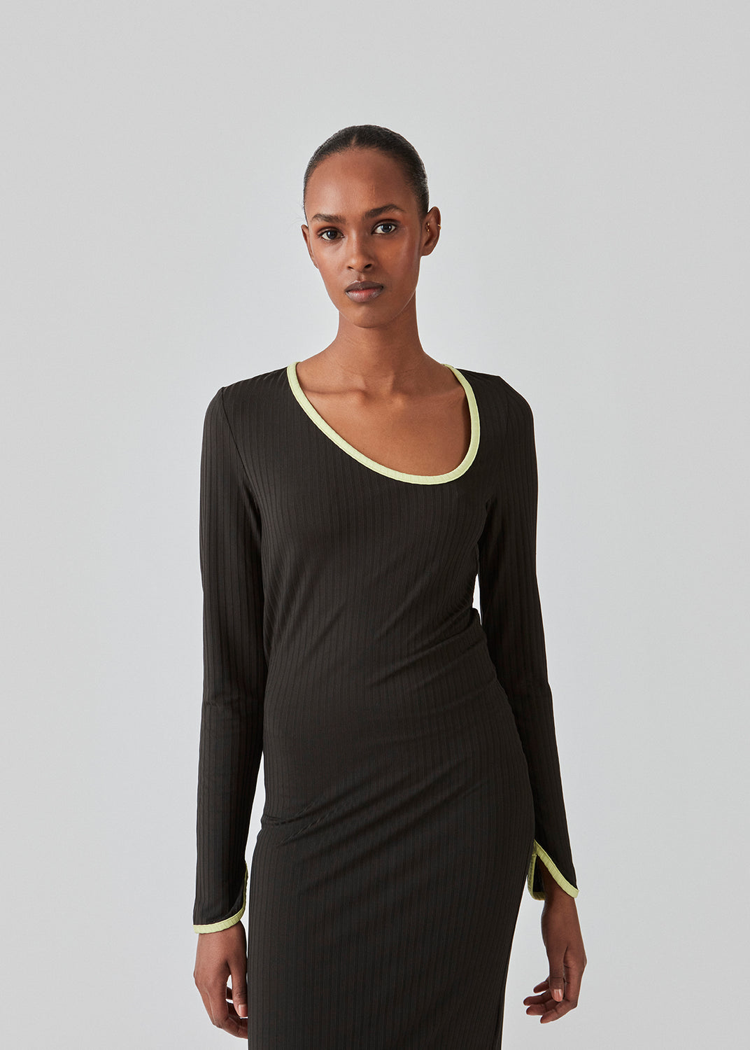 Tight-fitted maxi dress in stretchy rib. FaizMD dress has long sleeves with slit, slits at the sides of the skirt and an asymmetrical neckline with contrasting bias tape. The model is 175 cm and wears a size S/36.