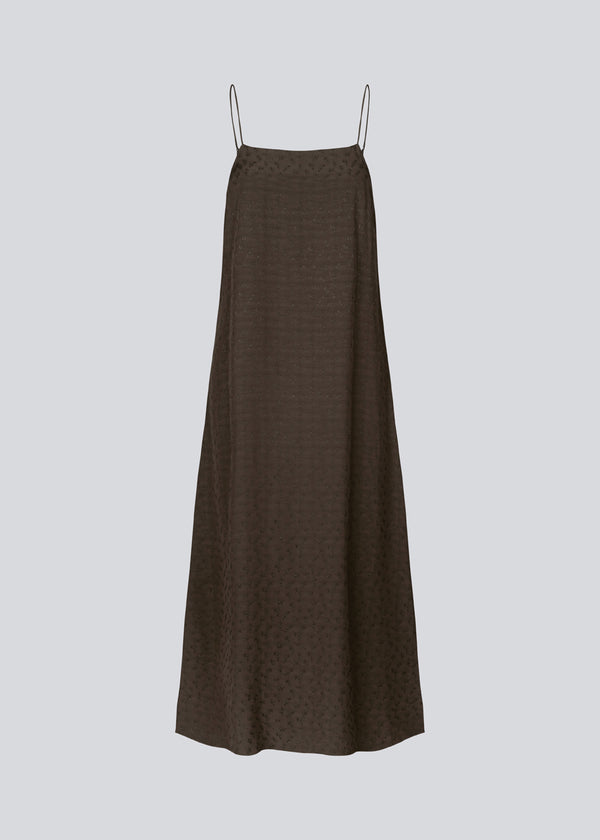 Long strap dress in brown in satin with woven pattern and a loose silhouette. FallowMD dress is styled with thin straps. The dress is lined. The model is 175 cm and wears a size S/36.
