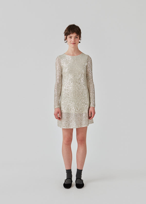 Short dress with sequins. FannieMD dress has a slim silhouette with a round neck and long sleeves, along with a keyhole opening at the back with a button for closure. The model is 175 cm and wears a size S/36.