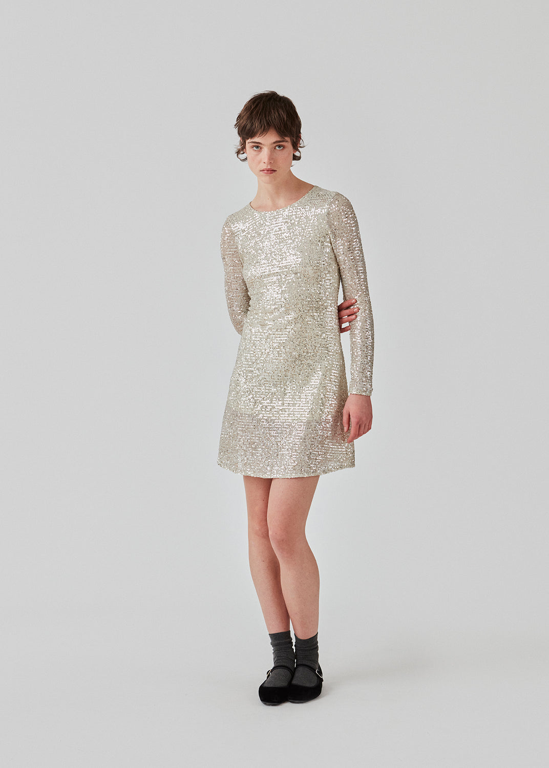 Short dress with sequins. FannieMD dress has a slim silhouette with a round neck and long sleeves, along with a keyhole opening at the back with a button for closure. The model is 175 cm and wears a size S/36.