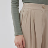 FanyaMD pants in bright beige have a menswear-inspired look with straight, wide legs, a high waist with zip fly and button and elastication in back. Doubble pleat in front and side pockets. The model is 175 cm and wears a size S/36.