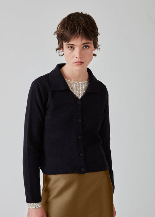 Fine knit cardigan in navy blue with a v-neckline and collar. FaroMD cardigan has a relaxed shape with matching buttons in front and ribbed trimmings. The model is 175 cm and wears a size S/36.