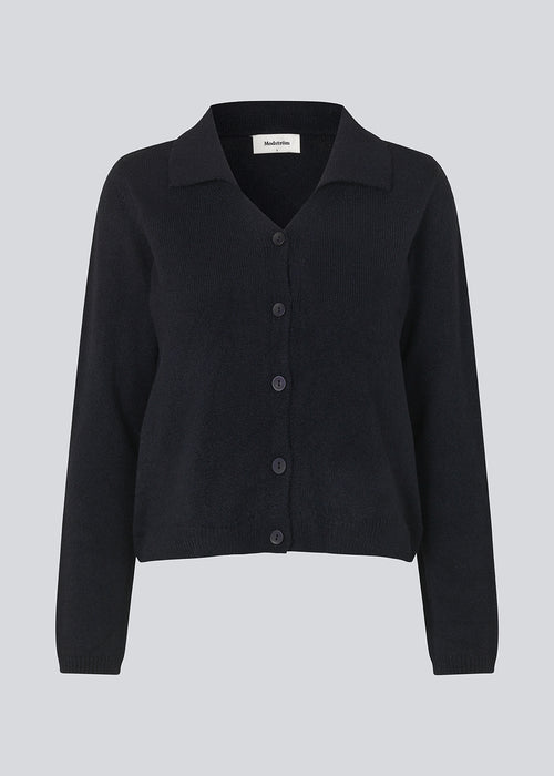 Fine knit cardigan in navy blue with a v-neckline and collar. FaroMD cardigan has a relaxed shape with matching buttons in front and ribbed trimmings. The model is 175 cm and wears a size S/36.