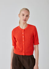 Short sleeved cardigan in bright cherry knitted from an organic cotton with eyelet pattern. FaxonMD cardigan features a round neck with buttons in front. The model is 175 cm and wears a size S/36.