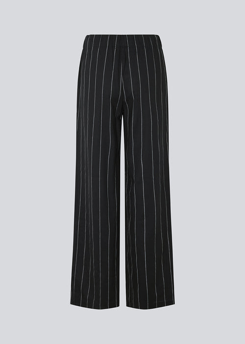 FiaMD pants in bkack have a loose fit in a linen mix with vertical stripes. The pants have an elasticated waist with tiebelt and side pockets. The model is 177 cm and wears a size S/36.