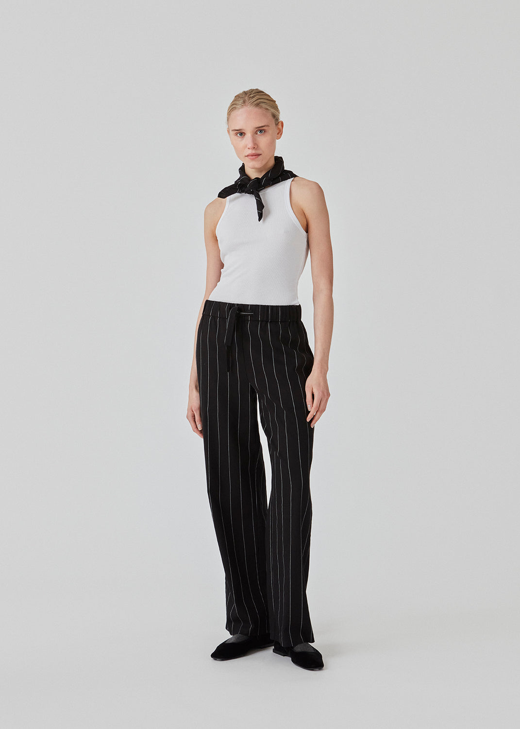 FiaMD pants in bkack have a loose fit in a linen mix with vertical stripes. The pants have an elasticated waist with tiebelt and side pockets. The model is 177 cm and wears a size S/36.