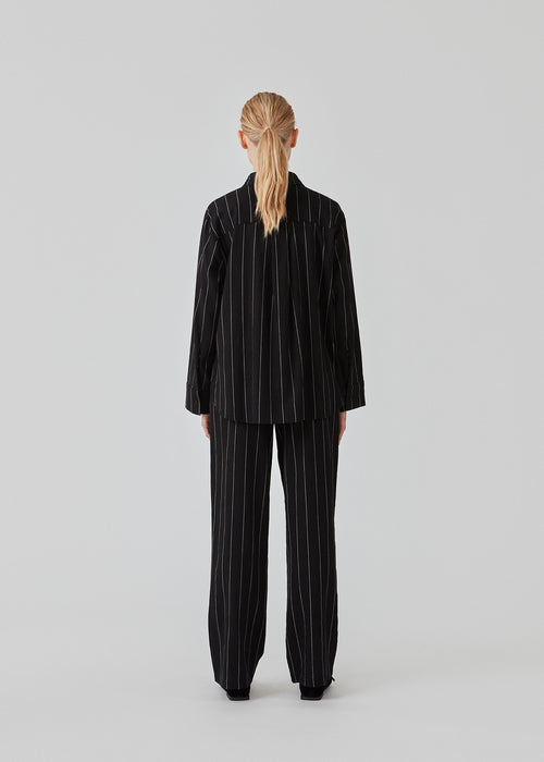 FiaMD pants in bkack have a loose fit in a linen mix with vertical stripes. The pants have an elasticated waist with tiebelt and side pockets. The model is 177 cm and wears a size S/36.