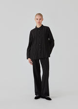 FiaMD pants in bkack have a loose fit in a linen mix with vertical stripes. The pants have an elasticated waist with tiebelt and side pockets. The model is 177 cm and wears a size S/36.