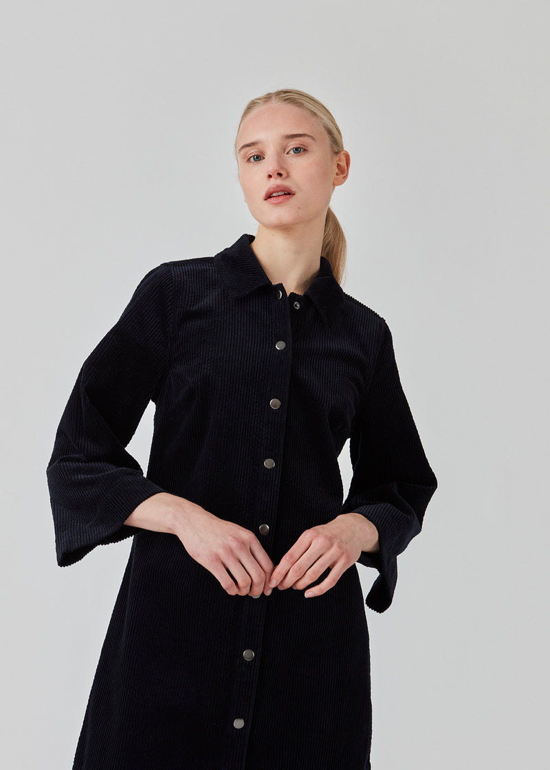 Midi shirt dress in navy sky in corduroy with collar and press-studs in front. FikaMD dress has a loose A-line silhouette and 3/4 length wide sleeves. The model is 175 cm and wears a size S/36.