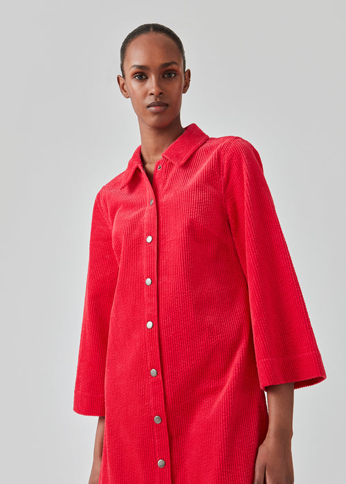 Pink midi shirt dress in corduroy with collar and press-studs in front. FikaMD dress has a loose A-line silhouette and 3/4 length wide sleeves. The model is 175 cm and wears a size S/36.