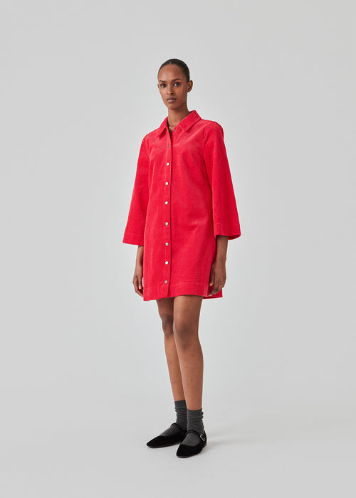 Pink midi shirt dress in corduroy with collar and press-studs in front. FikaMD dress has a loose A-line silhouette and 3/4 length wide sleeves. The model is 175 cm and wears a size S/36.