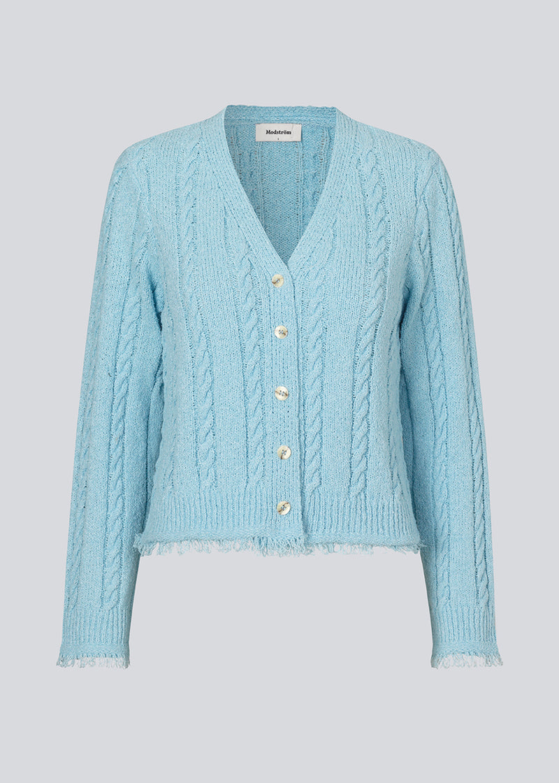 Light blue cardigan in cotton cable knit. Oversized and slightly cropped shape with long sleeves and raw trimmings. FinaMD cardigan has a v-neckline and buttons in front. The model is 175 cm and wears a size S/36.