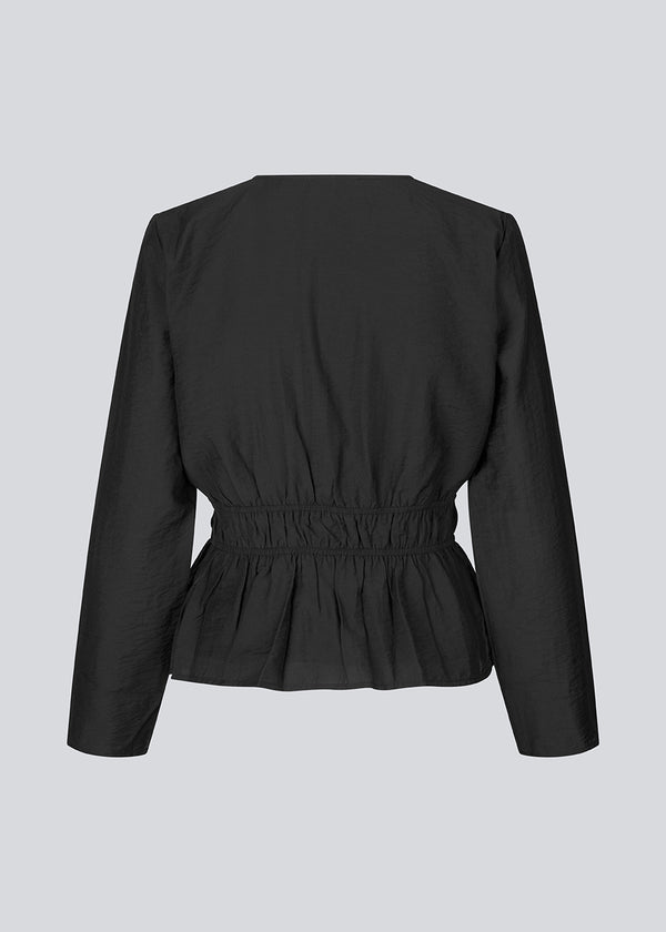 Tight-fitted top in black in a light woven quality with a deep v-neck and detailing at chest and waist for a tailored effect. FinnMD top is lined. 