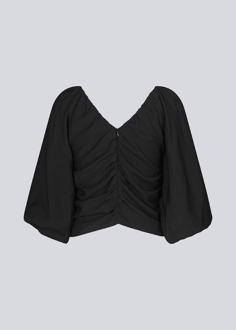 Long sleeved top in black in woven quality with long, voluminous sleeves. FisherMD top has a v-neckline in front and back with ruched seams, adding a drapy effect.