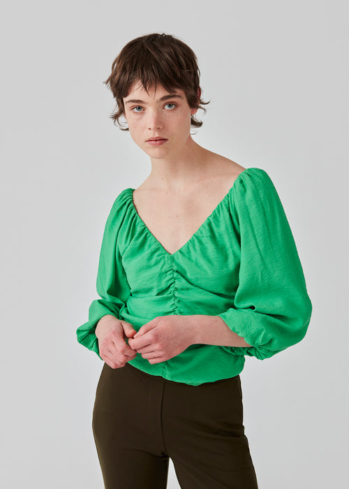 Long sleeved top in woven quality with long, voluminous sleeves. FisherMD top has a v-neckline in front and back with ruched seams, adding a drapy effect. The model is 175 cm and wears a size S/36.