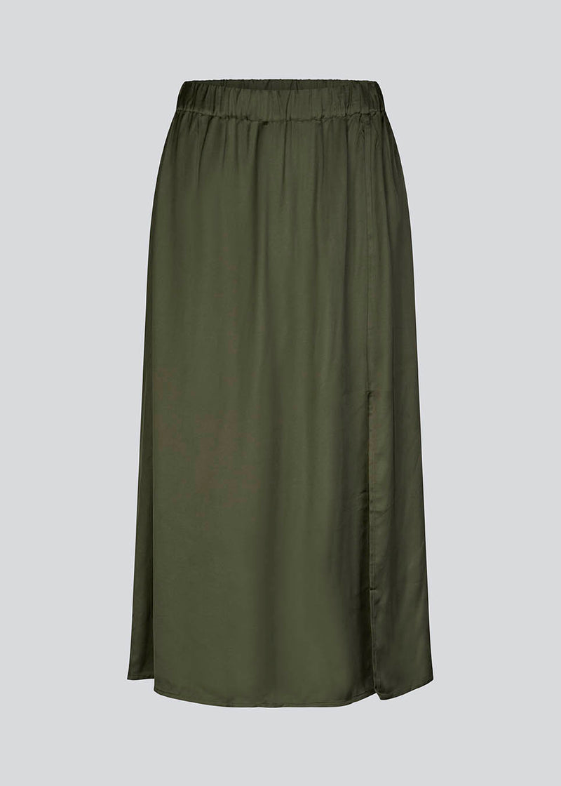 Satin skirt in dark green with volume in the skirt and a slit in front. FloreMD skirt is medium length and high-waisted with covered elastication. 