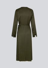 Long dress in dark green in a satin-woven EcoVero viscose blend. FloreMD wrap dress has a v-neckline and wrap detail with a thin tie belt. Long sleeves with a slit at the hem. 