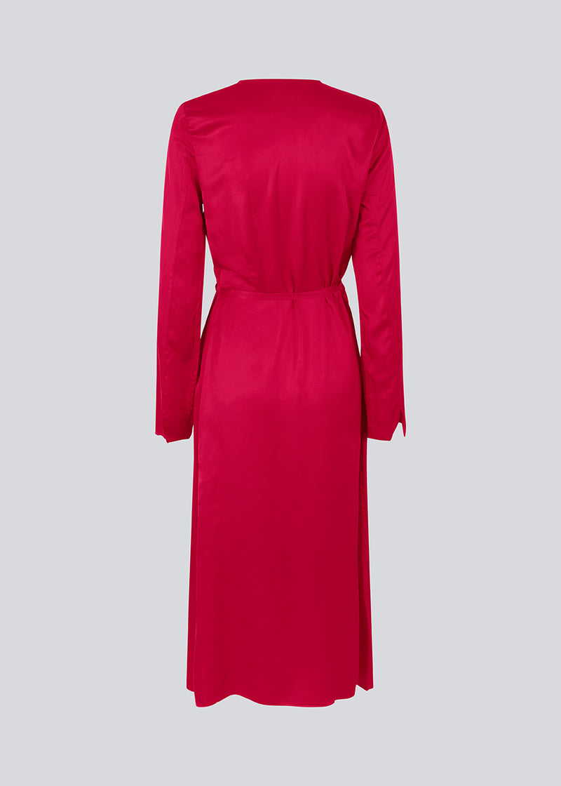 Long dress in pink in a satin-woven EcoVero viscose blend. FloreMD wrap dress has a v-neckline and wrap detail with a thin tie belt. Long sleeves with a slit at the hem. The model is 175 cm and wears a size S/36.