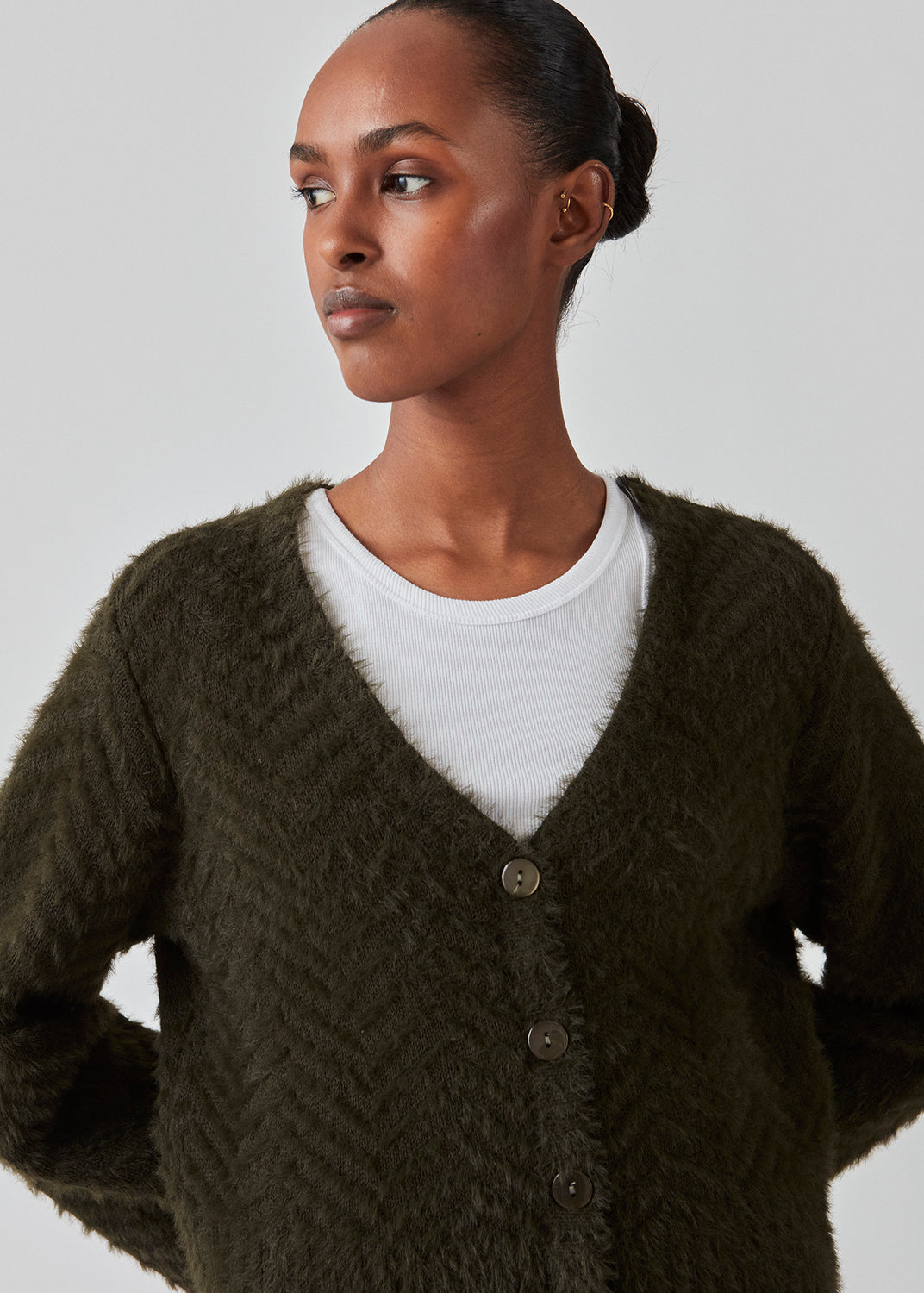 Fluffy cardigan in cotton blend in dark green. FloriaMD cardigan has a rounded shape, v-neckline, long wide sleeves and buttons in front. The model is 175 cm and wears a size S/36.