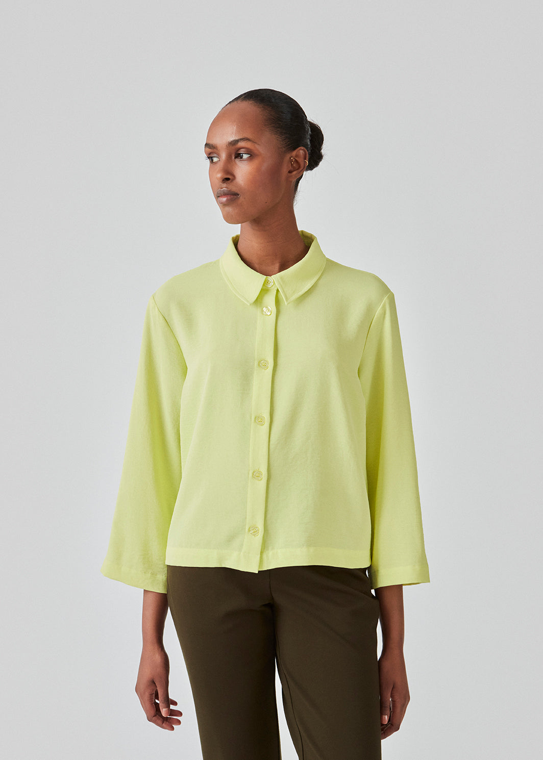 Cropped shirt in light yellow with a flowy and relaxed fit. FredaMD shirt has a collar and button closure in front, along with 3/4 length wide sleeves. The model is 175 cm and wears a size S/36.