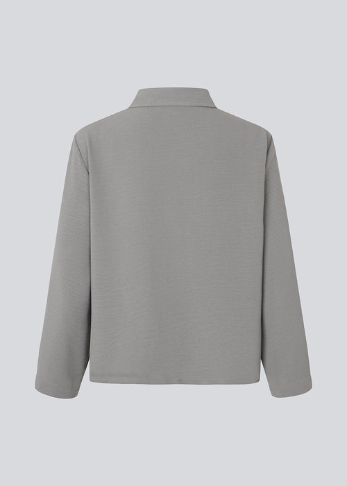 Cropped grey shirt with a flowy and relaxed fit. FredaMD shirt has a collar and button closure in front, along with 3/4 length wide sleeves. The model is 175 cm and wears a size S/36.