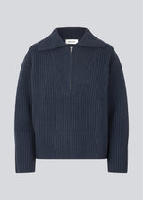 FultonMD t-neck in navy sky is a chunky knit with a wide shape. The jumper has a half-zip front, wide collar and long sleeves. The model is 175 cm and wears a size S/36.