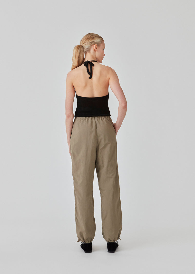 Parachute pants in beige in nylon with a relaxed fit. FumikoMD pants have a regular waist with elastic, wide legs and elastic drawstring at the waist. The model is 175 cm and wears a size S/36.
