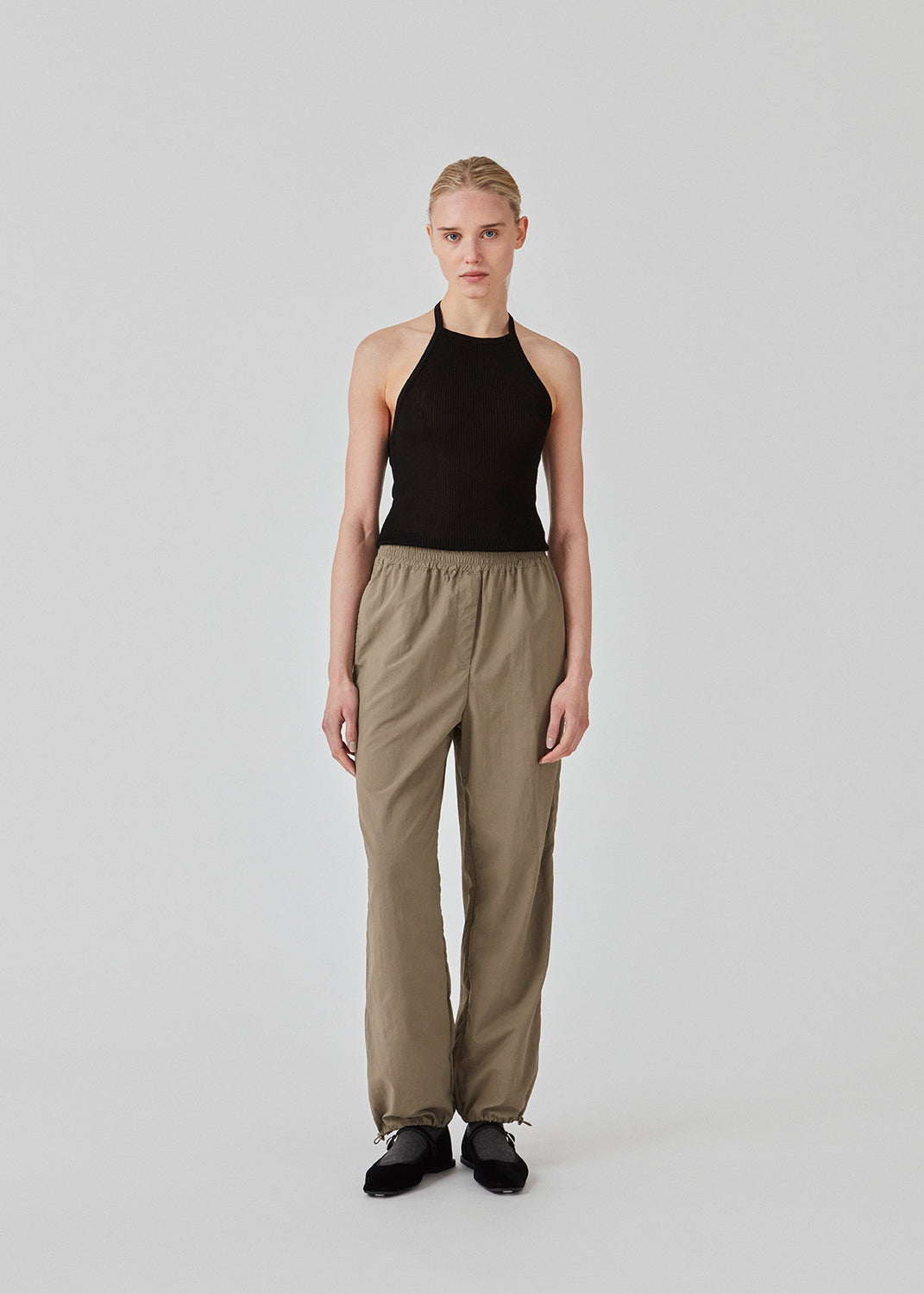 Parachute pants in beige in nylon with a relaxed fit. FumikoMD pants have a regular waist with elastic, wide legs and elastic drawstring at the waist. The model is 175 cm and wears a size S/36.