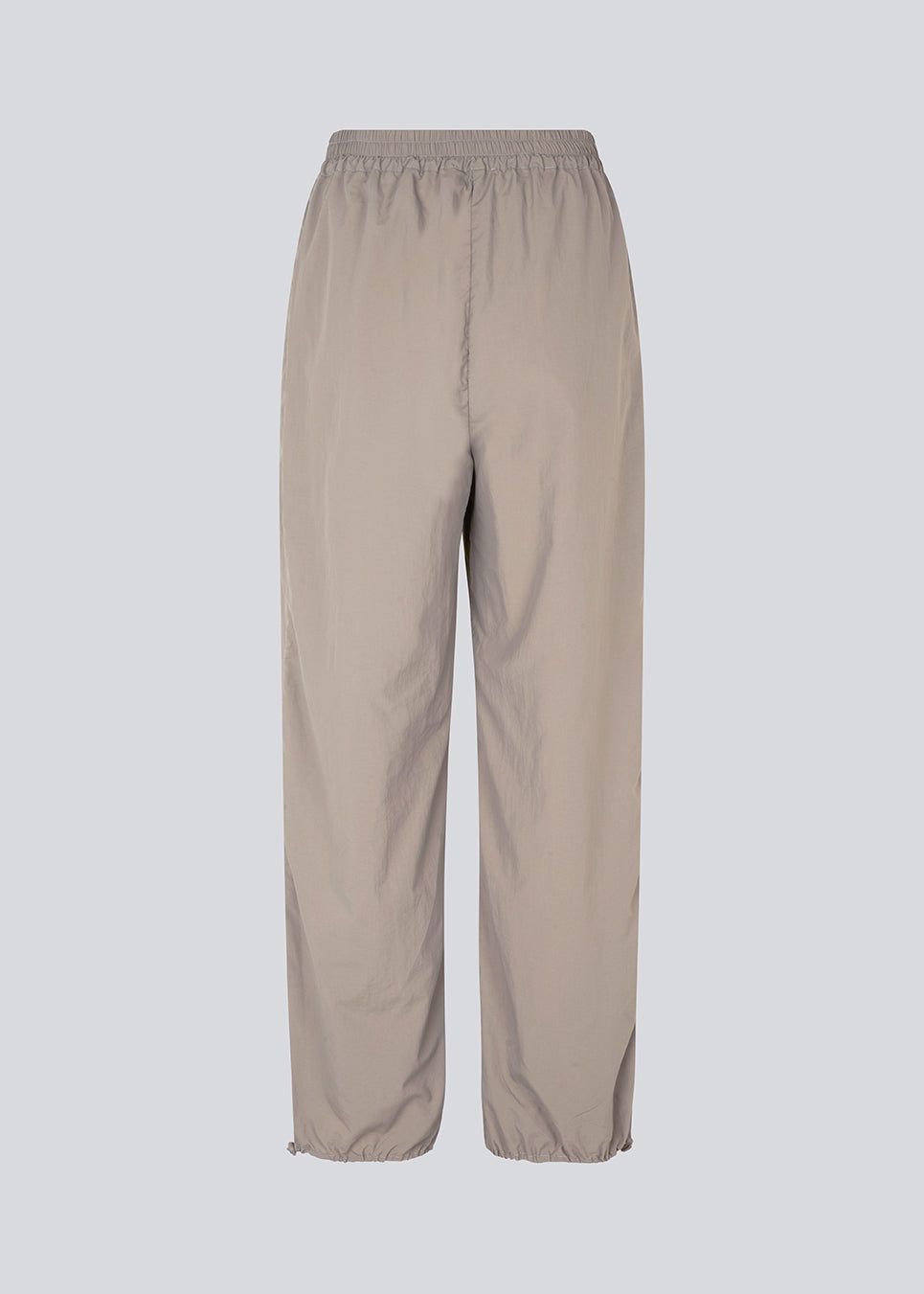 Parachute pants in beige in nylon with a relaxed fit. FumikoMD pants have a regular waist with elastic, wide legs and elastic drawstring at the waist. The model is 175 cm and wears a size S/36.