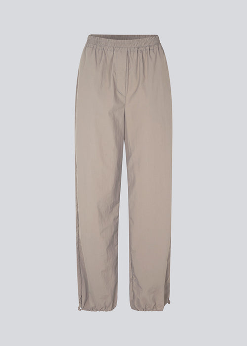 Parachute pants in beige in nylon with a relaxed fit. FumikoMD pants have a regular waist with elastic, wide legs and elastic drawstring at the waist. The model is 175 cm and wears a size S/36.