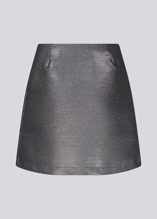 GabbieMD skirt cut for a mini silhuet with a high waist and concealed zipper in a structured and shiny material. Lined. The model is 175 cm and wears a size S/36.
