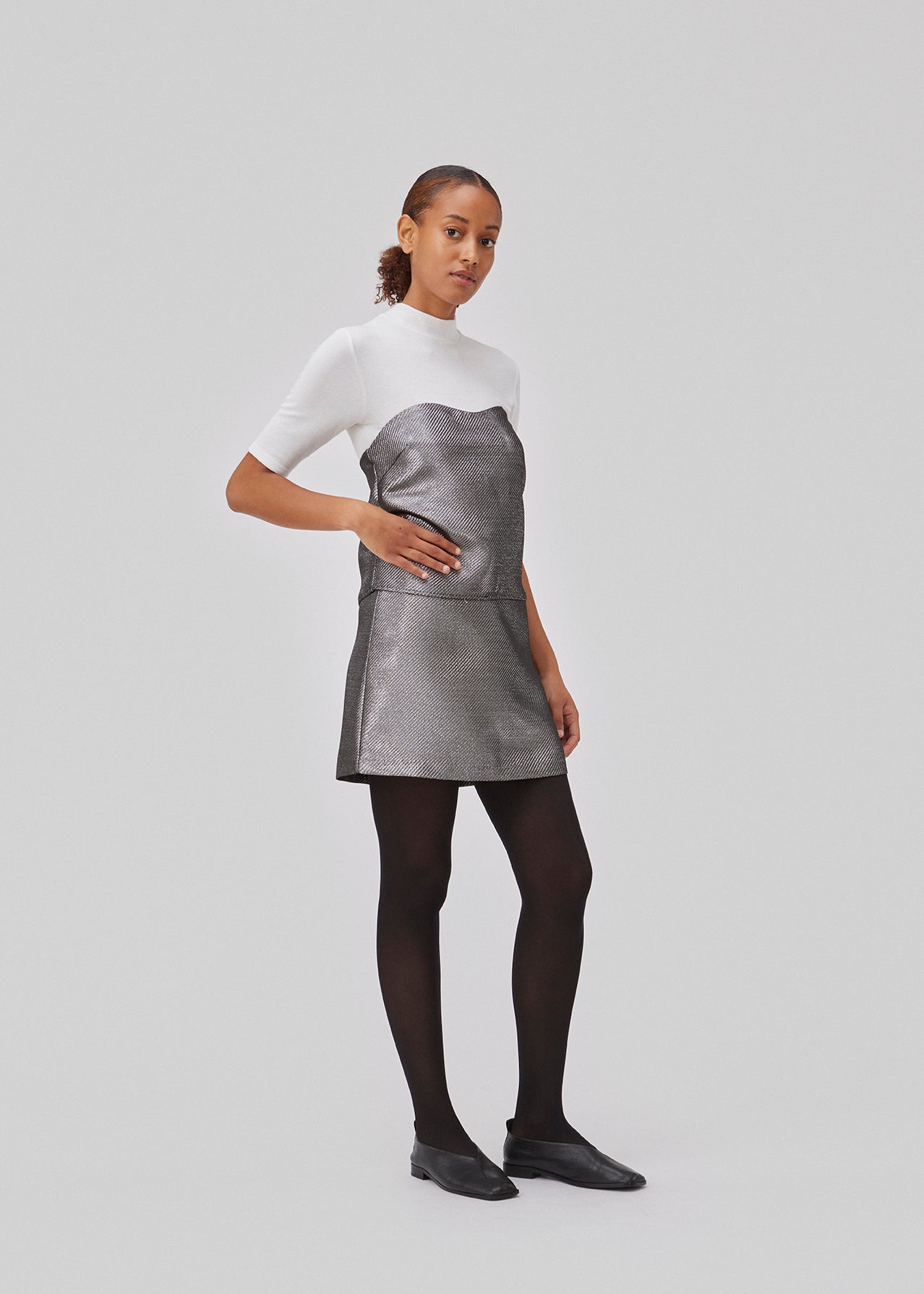 GabbieMD skirt cut for a mini silhuet with a high waist and concealed zipper in a structured and shiny material. Lined. The model is 175 cm and wears a size S/36.