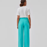 Gale pants in turquoise have a classic design. The pants have straight, wide legs with press folds, which creates an elegant look. The model is 175 cm and wears a size S/36.  Shop matching blazer: Gale blazer.