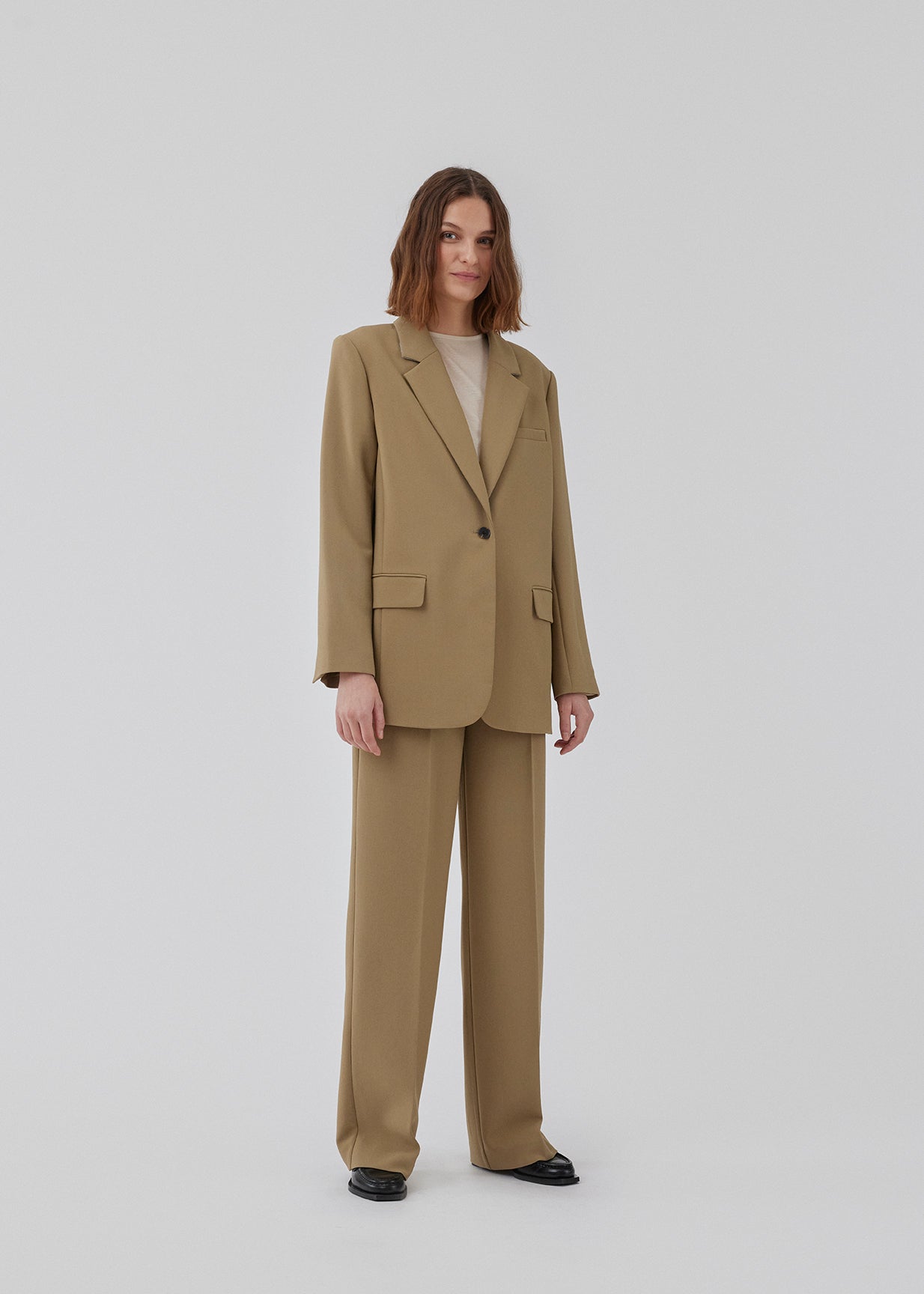 Gale pants in the color Dune have a classic design. The pants have straight, wide legs with press folds, which creates an elegant look. The model is 177 cm and wears a size S/36.