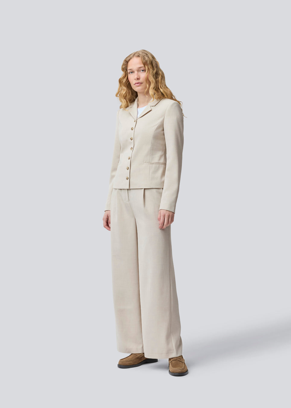GaleMD 2 short blazer features the classic Gale design but in a lighter quality. The blazer is fitted, slightly cropped, and has a button closure and two pockets in front. The blazer is light cream.