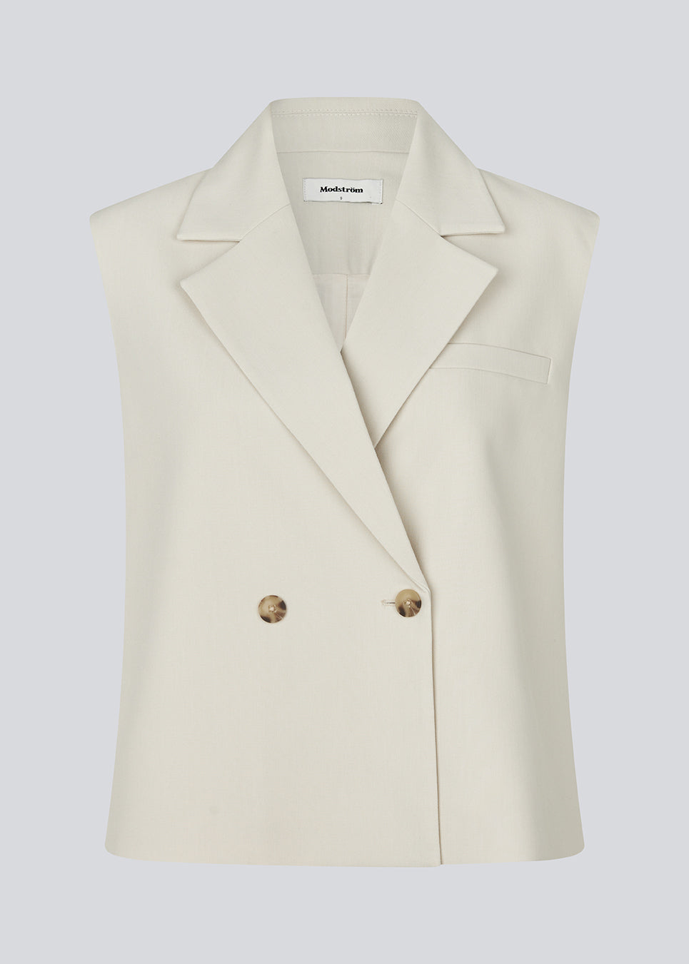 Loose vest in creme with a collar in our classic gale material. Galemd vest is sleeveless and has a front button closure. The model is 175 cm and wears a size S/36.

Material:
5% Elastane
76% Recycled Polyester
19% Viscose

Lining:
35% Polyester
65% Viscose