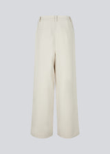 Suit pants in creme with pleats in classic gale material. Galemd wide pants has wide legs and side pockets. The model is 175 cm and wears a size S/36.

Material:
5% Elastane
76% Recycled Polyester
19% Rayon

Lining:
35% Polyester
65% Rayon