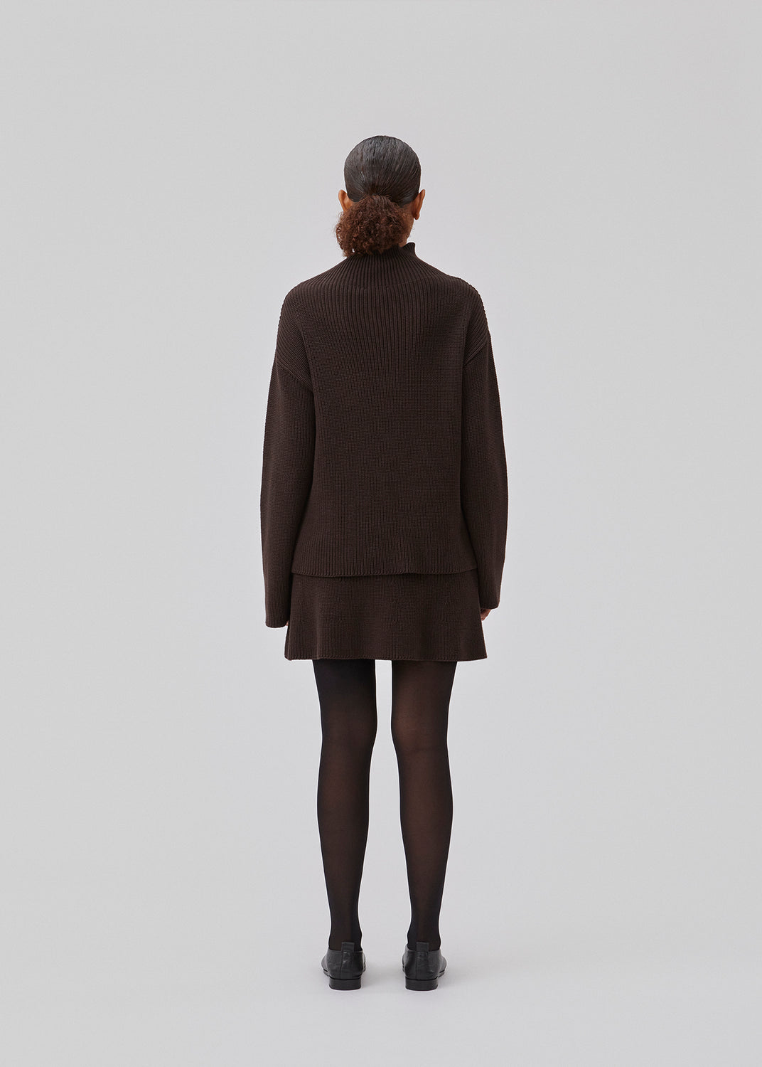 GalenMD t-neck in brown knitted from organic cotton with an oversized shape, lange and wide sleeves, along with a high neck and dropped shoulders. The model is 175 cm and wears a size S/36.