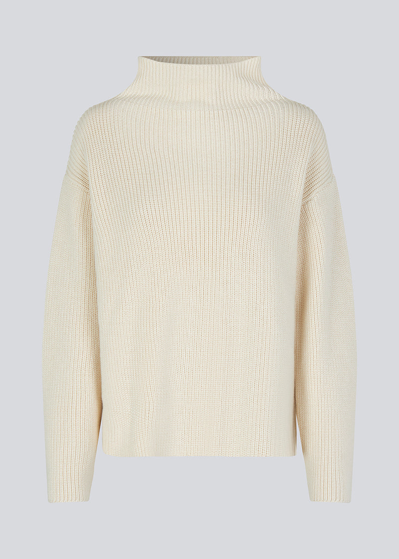 GalenMD t-neck in white knitted from organic cotton with an oversized shape, lange and wide sleeves, along with a high neck and dropped shoulders. The model is 175 cm and wears a size S/36.