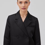 Cropped double-breasted blazer in a heavy satin. GavinMD blazer has a collar and lapels, fabric covered buttons in front and slits at cuffs. The model is 175 cm and wears a size S/36