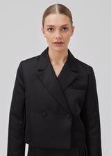 Cropped double-breasted blazer in a heavy satin. GavinMD blazer has a collar and lapels, fabric covered buttons in front and slits at cuffs. The model is 175 cm and wears a size S/36