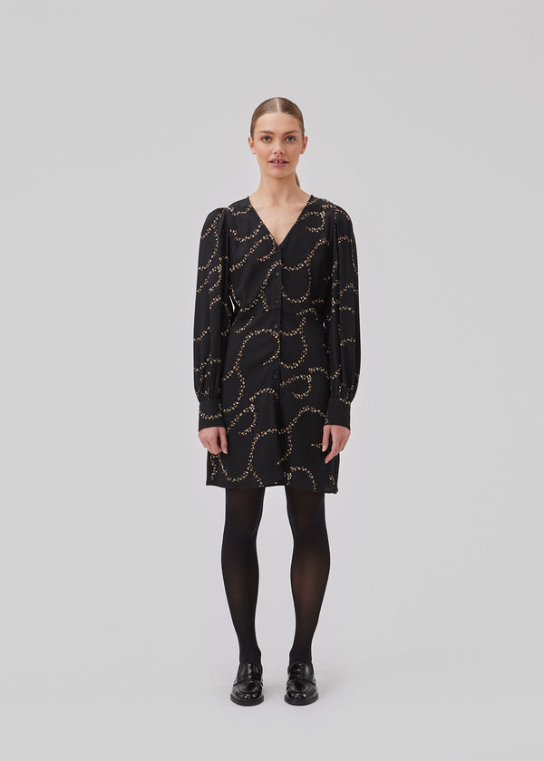 Short dress with a v-shaped neckline and buttons in front. GelilaMD print dress has long balloon sleeves with a wide cuff. The model is 175 cm and wears a size S/36.