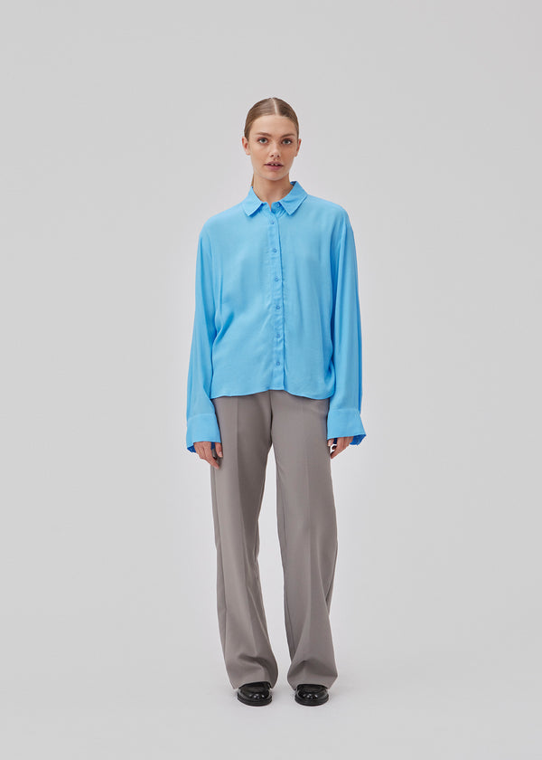 Oversized shirt with collar, button closure in front and wide sleeves with cuff. GelilaMD shirt has a casting with tiebelt with ruching at one side. The model is 175 cm and wears a size S/36.