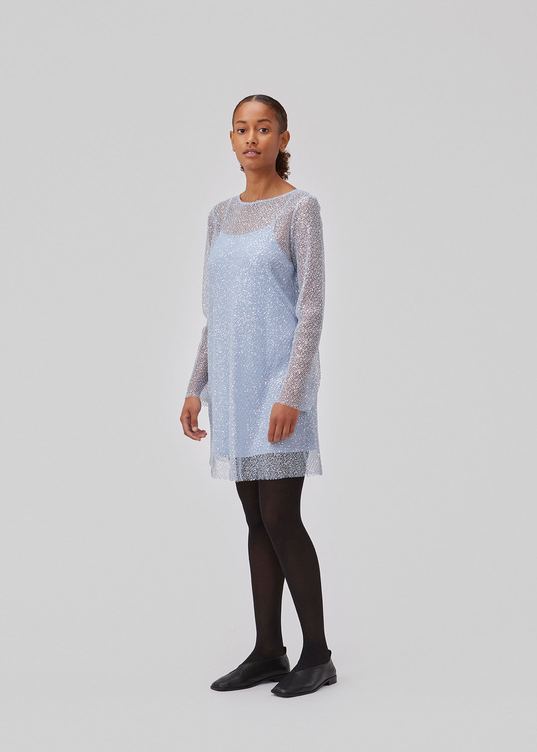 Mini dress in mesh covered in sequins. GerardMD dress has an A-line silhouette, long sleeves and a round neck with opening in the back. Detachable slip dress. The model is 175 cm and wears a size S/36.