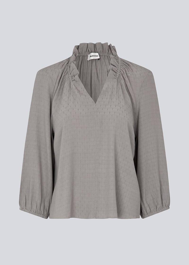 Top in grey with a relaxed fit. GilliganMD top has a v-shaped neckline with ruching around the neck and 3/4 length balloon sleeves with elastics at cuff. The model is 175 cm and wears a size S/36.