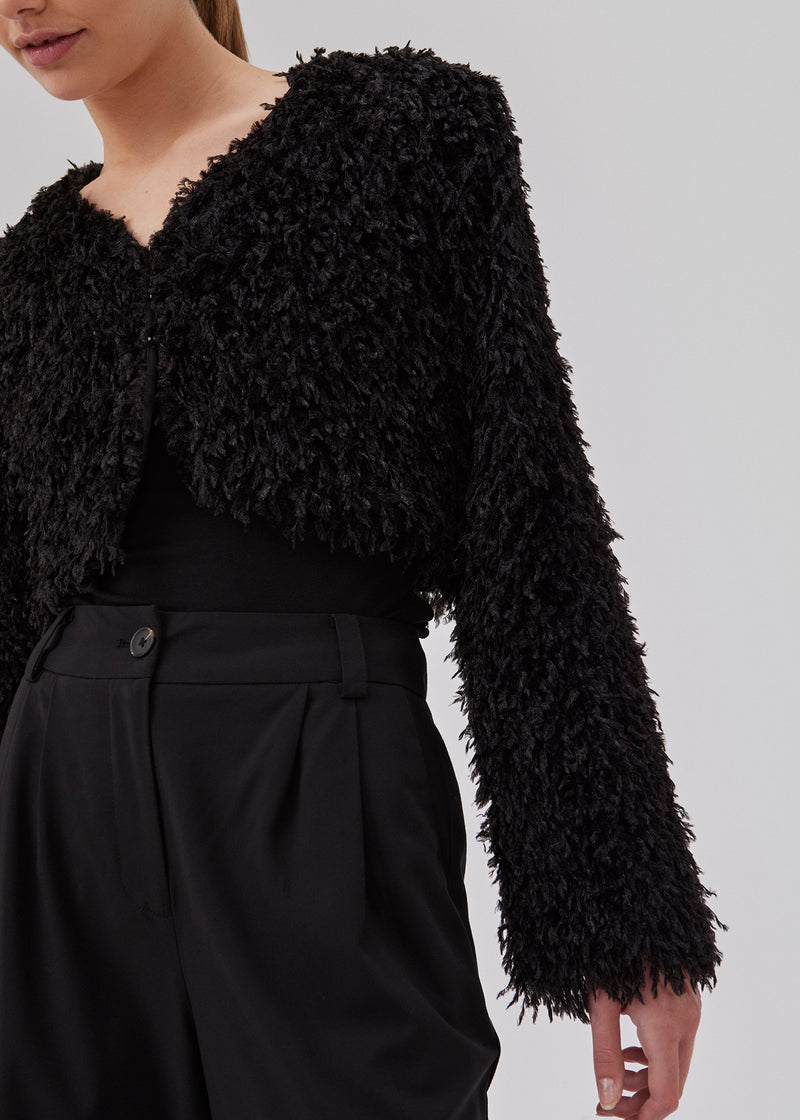 Cropped, light jacket in black in a feather-like quality. GinaMD jacket has long sleeves, v-neckline and hook and clasp closure in front. Rounded hems at the bottom. The model is 175 cm and wears a size S/36.