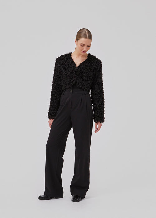 Cropped, light jacket in black in a feather-like quality. GinaMD jacket has long sleeves, v-neckline and hook and clasp closure in front. Rounded hems at the bottom. The model is 175 cm and wears a size S/36.