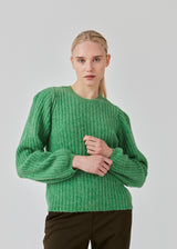 Simple rib knit in green with a slim silhouette, voluminous balloon sleeves and a round neckline. The trim on the sleeves and the neckline is knitted in a smaller rib. Goldie o-neck is made from an alpaca blend that adds a luxurious feel and looks.