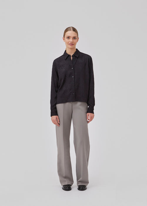 Shirt in black in jacquard satin in a slightly cropped length. GraceyMD shirt has a loose fit with long sleeves, cuff, collar and buttons in front. The model is 175 cm and wears a size S/36.