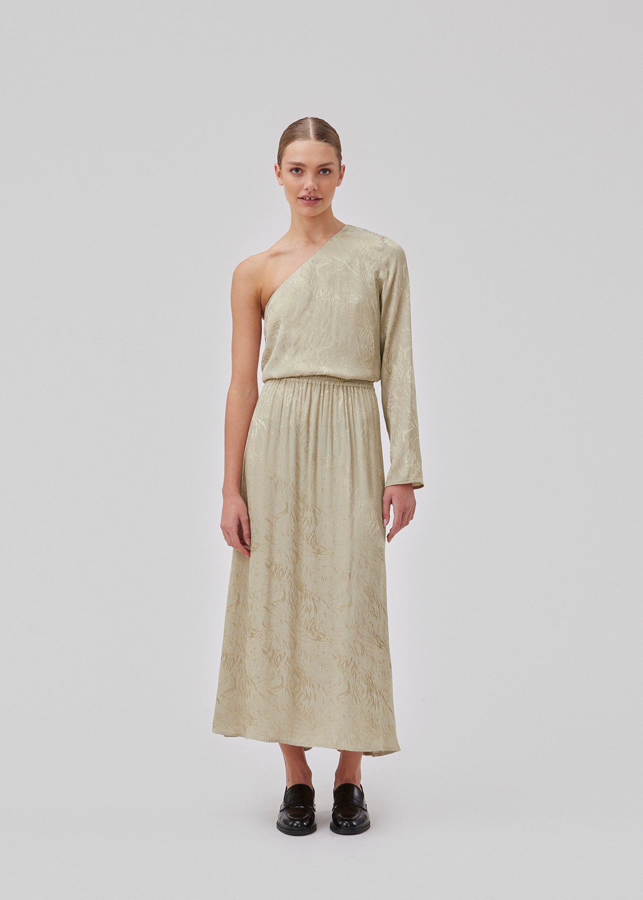 Top in spray green in shiny jacquard satin. GraceyMD top is designed with one bare shoulder and one long, wide sleeve. The fit is loose. The model is 175 cm and wears a size S/36.